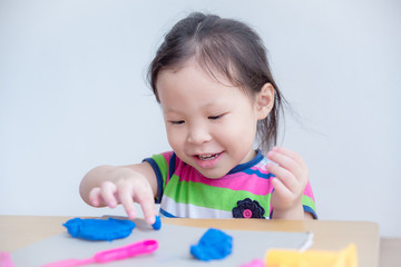 Wall Mural - Little asian girl playing with dough on table