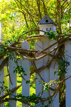 White Wooden Bird House On A Picket Fence Post
