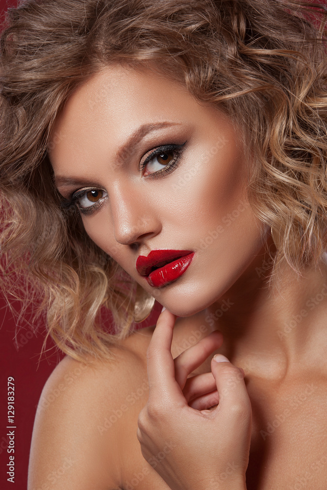 
Beautiful model girl with curly hair on a gray background with professional makeup. Portrait studio shot in close-up.