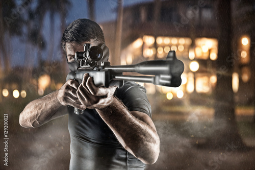 Fotografía Close-up of man in headgear aiming with sniper rifle