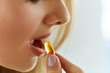 Close Up Of Beautiful Woman Taking Fish Oil Capsule In Mouth