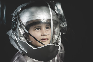 boy playing to be an astronaut with space helmet and metal suit