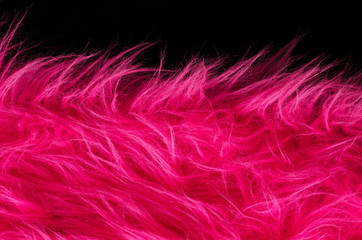 Pink plush fabric on black background horizontal. Very soft polyester textile made of synthetic fibers with long hairs. Macro close up material photography, front view.