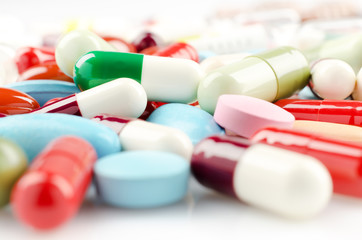 Wall Mural - Pharmacy theme. Multicolored Isolated Pills and Capsules on the White Surface. Closeup