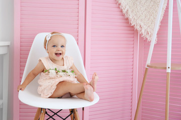 little baby girl sitting on chair on pink wooden screen background