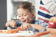 © PhotoAlto - Little girl slicing carrots in kitchen