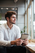 © Drobot Dean - Smiling businessman sitting in cafe and using tablet computer
