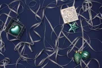 Christmas a composition of boxes and toys turquoise, decorated with silver ribbon curls. New year decor on a dark blue background. Top view, flat lay