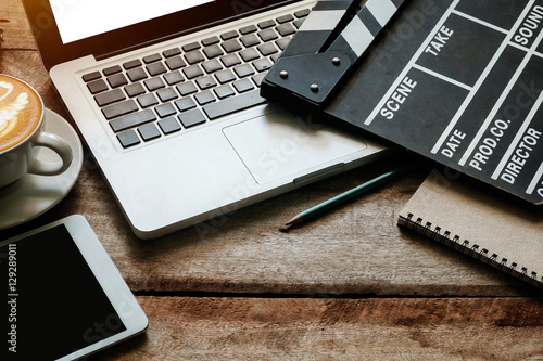 Fotomural Office things with movie clapper, laptop, tablet, coffee cup, pen and notepad on the wood table- top view shot