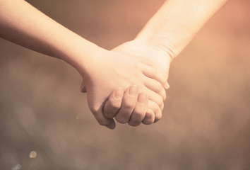 Mother holding a hand of his son in summer day outdoors