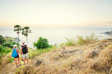 Wall Mural - Traveling and trekking concept. Two young people woman and man walking on mountains near the sea.