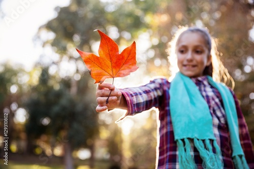 Fotografía Sonriente niña sosteniendo la hoja de otoño en el parque