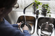 © Maskot - Cropped image of man washing utensils at kitchen sink