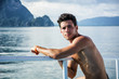 © theartofphoto - Portrait of young handsome bare-chested brunet man looking away against seascape on a boat or ship, leaning on handrail.