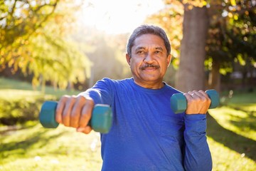 Mature man exercising with dumbbell at park