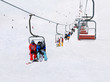 Chairlift (ski lift) transport skiers and snowboarders up a snowy downhill at winter ski snow Alpine resort, active seasonal outside sports background