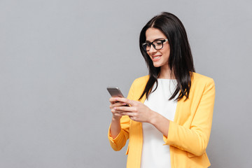 Wall Mural - Cheerful woman chatting by her phone over grey background