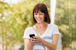 © mimagephotos - Laughing older woman messaging on smart phone