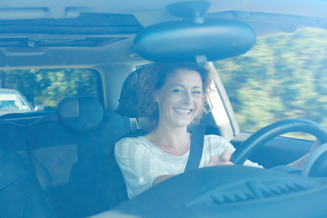 Wall Mural - Smiling older woman in car on commute