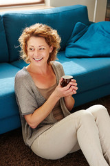 Wall Mural - Happy older woman at home holding coffee mug