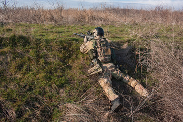 airsoft player in NATO uniform with rifle in ambush