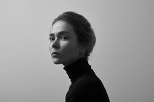 Dramatic Black And White Portrait Of Young Beautiful Girl With Freckles In A Black Turtleneck On White Background In Studio