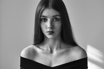 dramatic black and white portrait of a beautiful lonely girl with freckles isolated on a white backg