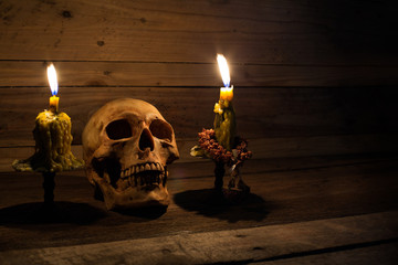 Two candles and skull on old wooden table