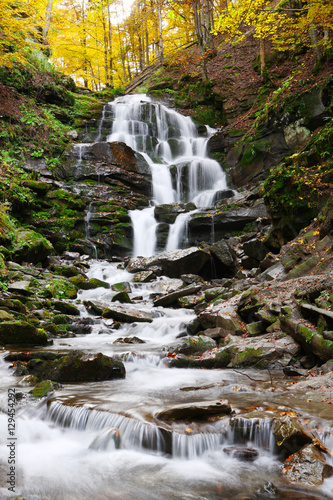 Naklejka nad blat kuchenny Beautiful view of the waterfall in the beech forest in the golden autumn season.