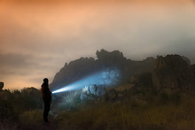 Man With A Flashlight At Night Standing On Mountains