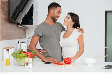 Wall Mural - Cheerful loving couple in the kitchen hugging while cooking