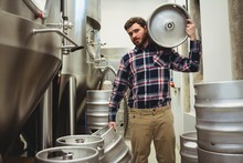 Young Manufacturer Carrying Kegs In Brewery