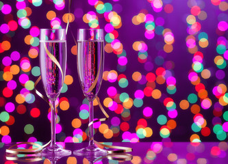 Two full champagne glasses with bokeh lights in the background