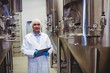 © WavebreakMediaMicro - Smiling manufacturer writing while standing at brewery