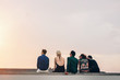 Friends sitting together on rooftop at sunset