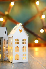 Wall Mural - little toy Christmas houses with a burning light inside is on blured green background