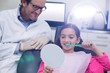 © WavebreakMediaMicro - Dentist assisting young patient while brush teeth