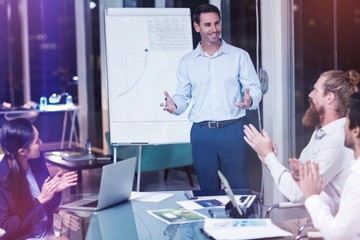 Coworkers applauding colleague at presentation