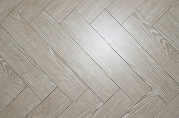 Beige floor tiles arranged in herringbone with look of parquet