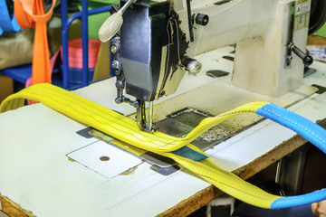 Industrial sewing machine sews a ratchet strap.