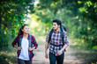 Young couple walking with backpacks in forest. Adventure hikes,