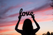 Female silhouette on sunset background with the word love in han