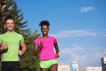 young smiling multiethnic couple jogging in the city