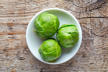 Wall Mural - Bowl of Brussels sprouts on wooden table, from above