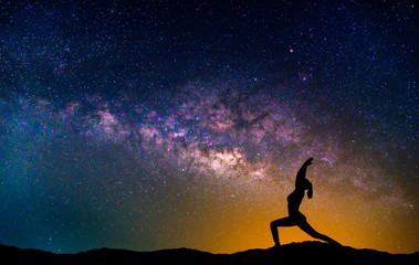 Wall Mural - landscape with milky way galaxy. night sky with stars and silhouette woman practicing yoga on the mo