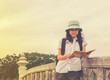 © chanyutcb - Happy travel woman reading book on old concrete bridge