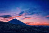 Fototapeta  - Silhouette of volcano del Teide against a sunset sky. Pico del Teide mountain in El Teide National park at night. Night landscape background with milky way on the sky. Tenerife, Canary Islands, Spain