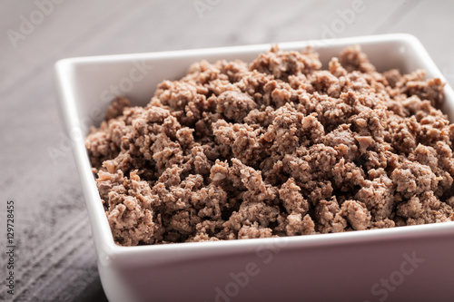 Fotografie, Obraz Macro shot of small white bowl of cooked ground meat on brown wooden table