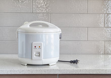 Electric rice cooker on granite counter-top against ceramic back