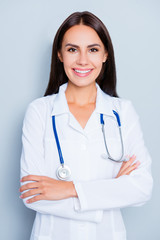 Wall Mural - Portrait of pretty female doctor with beaming smile and crossed